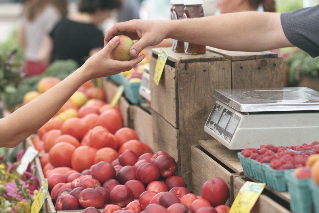 A local merchant sells a woman a fresh, locally grown apple.