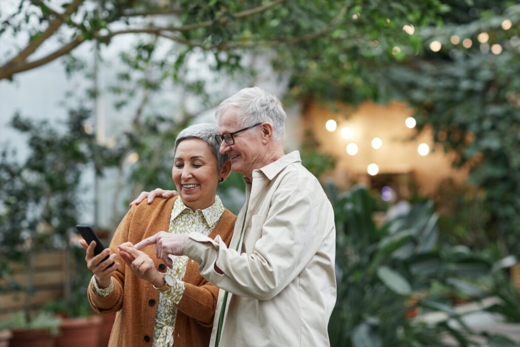 An older couple look smilingly at their smartphone, capturing their favorite bird sightings on the eBird app. 