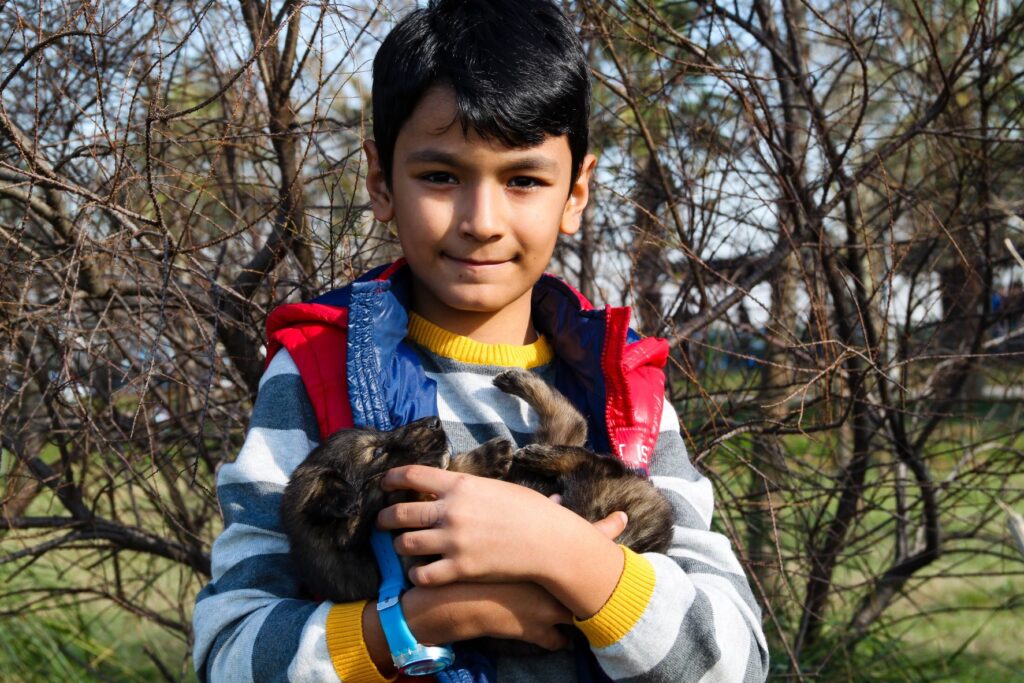 A young boy smiles at the camera while cradling a puppy in his arms. 