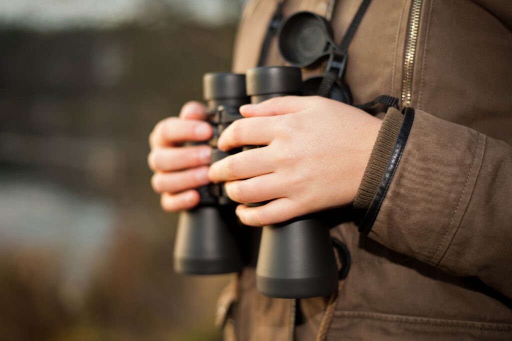 A young boy's hands cradle a pair of binoculars, perfect for birdwatching while out in nature or in your own backyard.