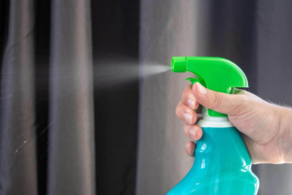 A hand sprays a non-chemical treatment with a spray bottle. 