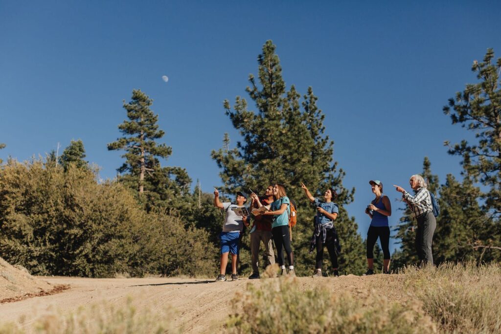 An excited group gathers and points out nearby birds on a guided Chirp bird walk through the Big Bear Lake area.