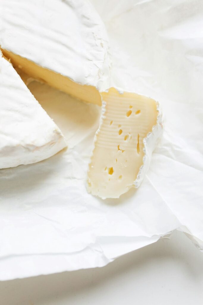 A wheel of brie cheese with a piece sliced out, ready to be eaten.