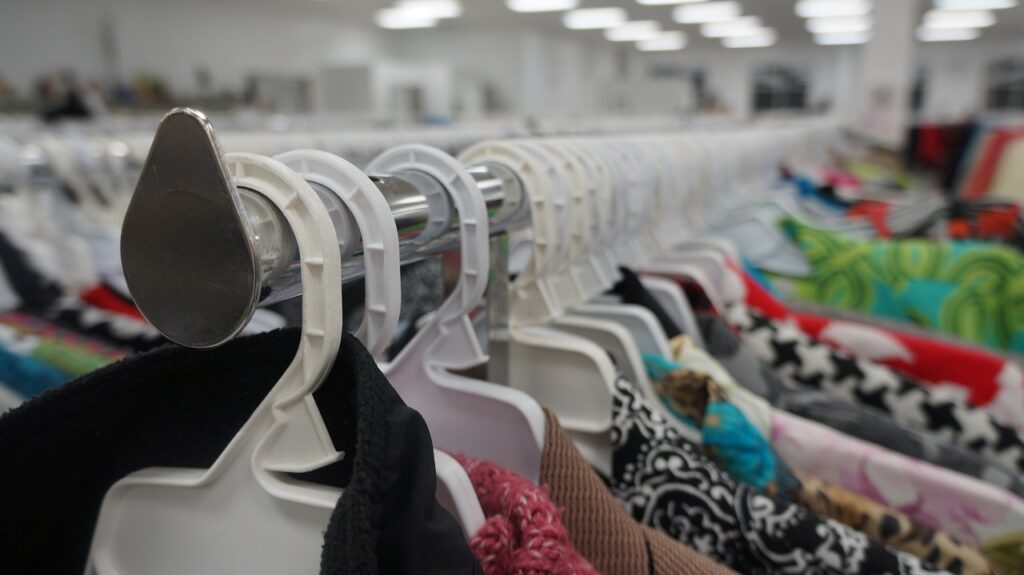 A row of clothing on hangers in a thrift store.