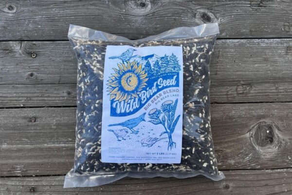 A 5-lb bag of Chirp's Big Bear Blend bird seed on wooden flooring.