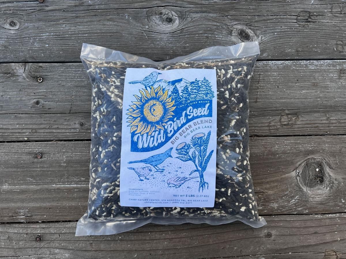 A 5-lb bag of Chirp's Big Bear Blend bird seed on wooden flooring.