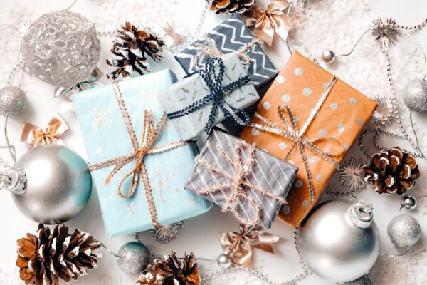 Wrapped holiday gifts on a white snowy background with painted pine cones.